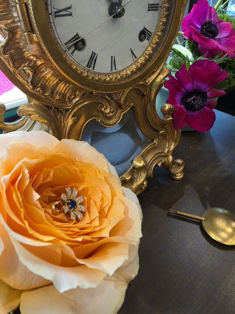 Rosa color melocotón con un colgante de joyería y un reloj antiguo dorado: flores y joyería del atelier IDEM